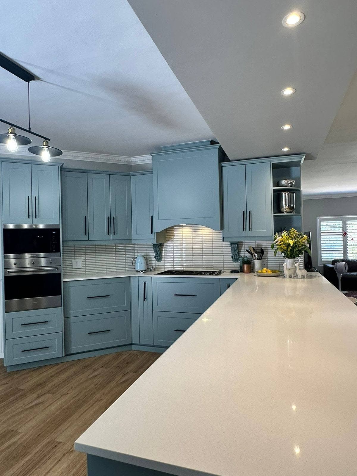 Grey shaker-style kitchen cabinets with a long white stone island