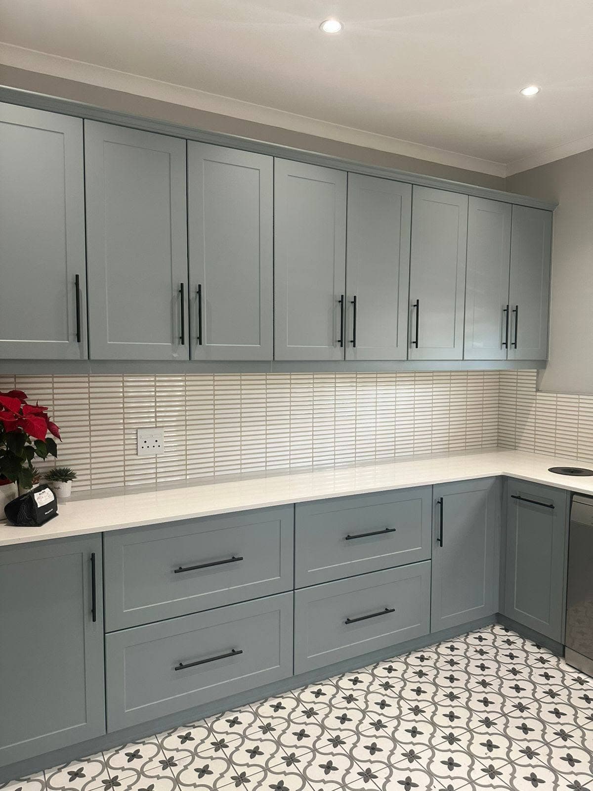 A long run of grey kitchen cupboards with black handles